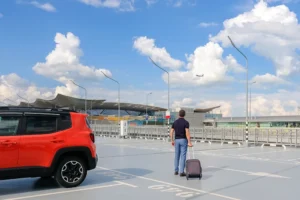 Ein Mann mit einem Koffer auf dem Flughafenparkplatz