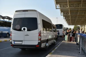 Reisende steigen mit Gepäck in einen Shuttlebus auf einem Flughafenparkplatz in Nürnberg